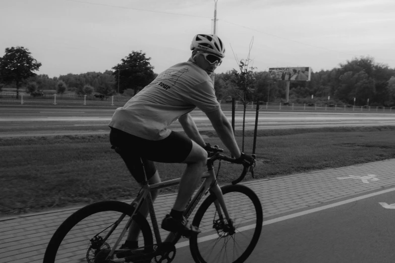 a black and white image of a cyclist on a sidewalk