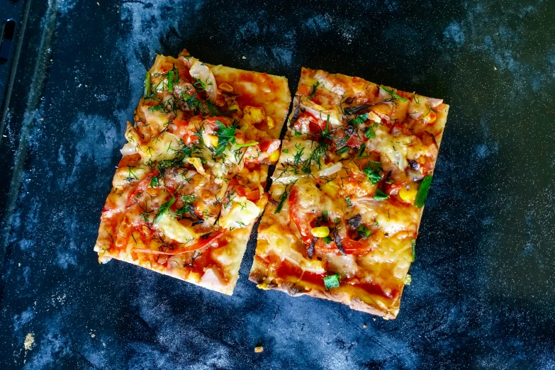 two sliced thin crust pizza sitting on top of a baking pan