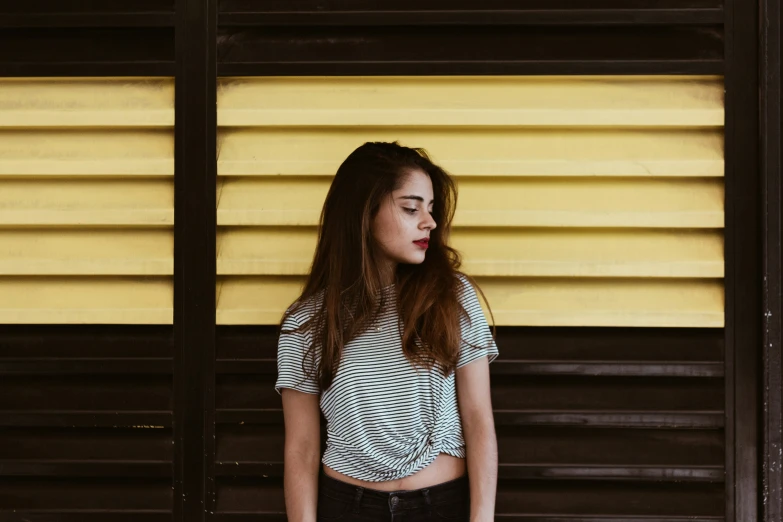 the woman in the black pants is standing against a yellow wall