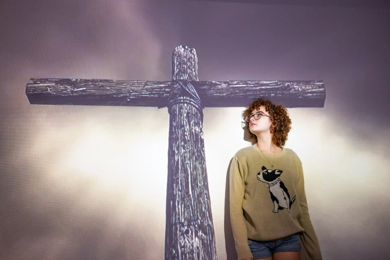 a young man standing in front of a giant wooden cross