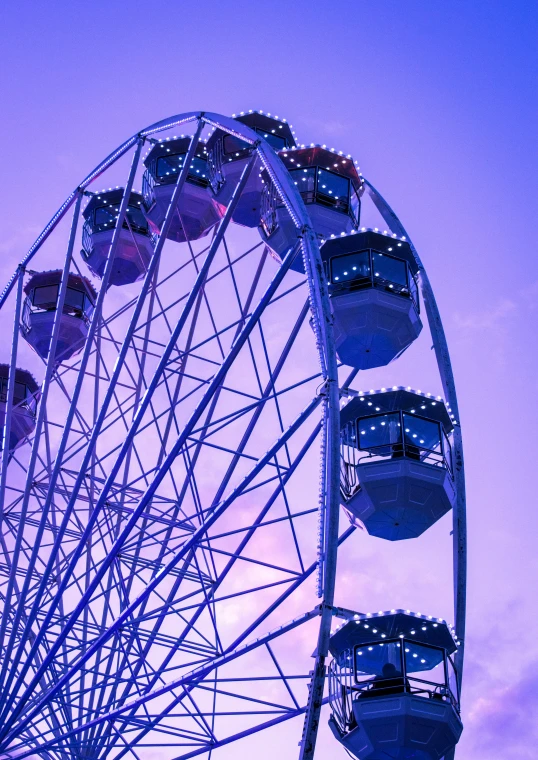 a large ferris wheel sitting in the middle of a purple sky