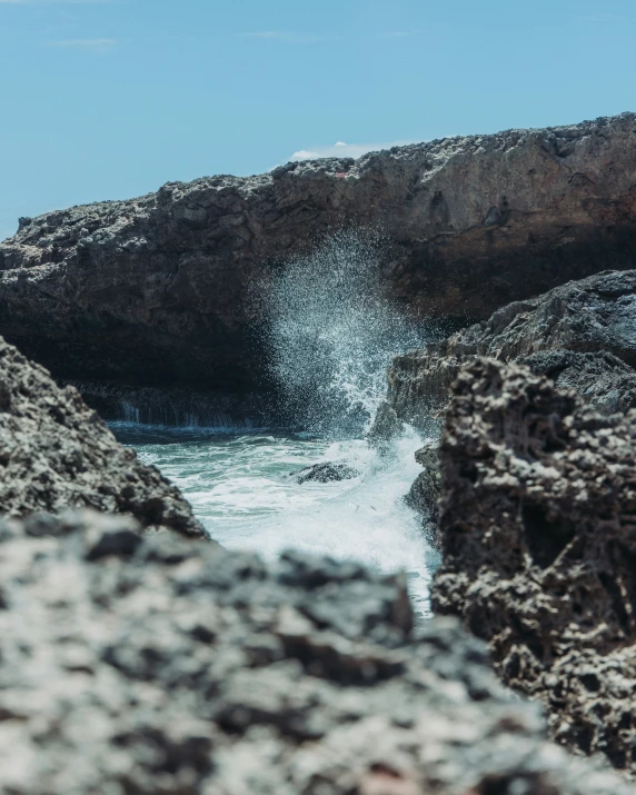 two people walking along the coast next to some rocks