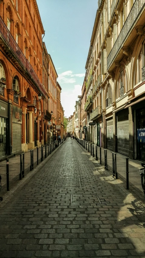 a brick street with tall buildings along it