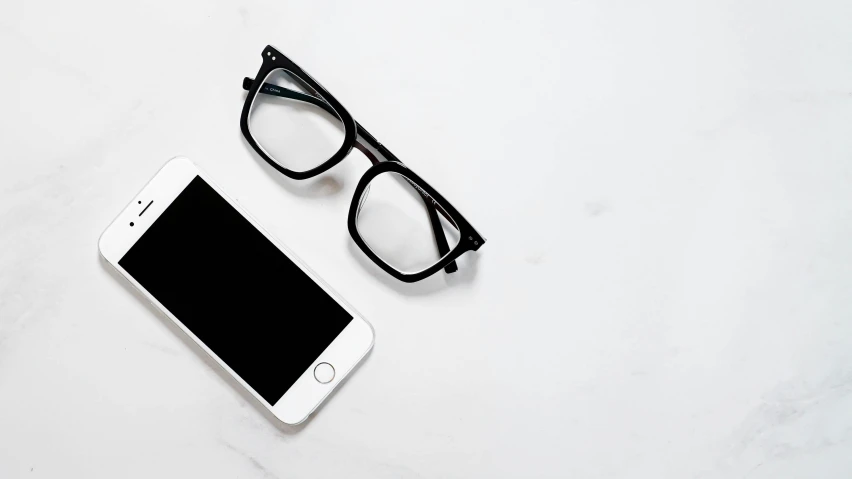 glasses, cellphone and tablet on a white table