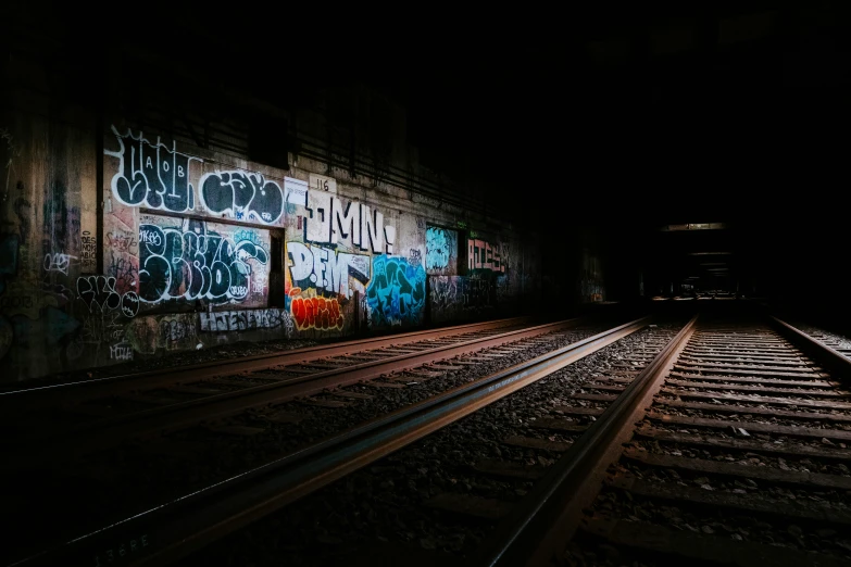 two train tracks that are near a wall