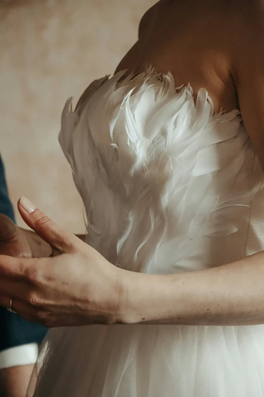 a woman dressed in a white wedding gown standing in front of the groom