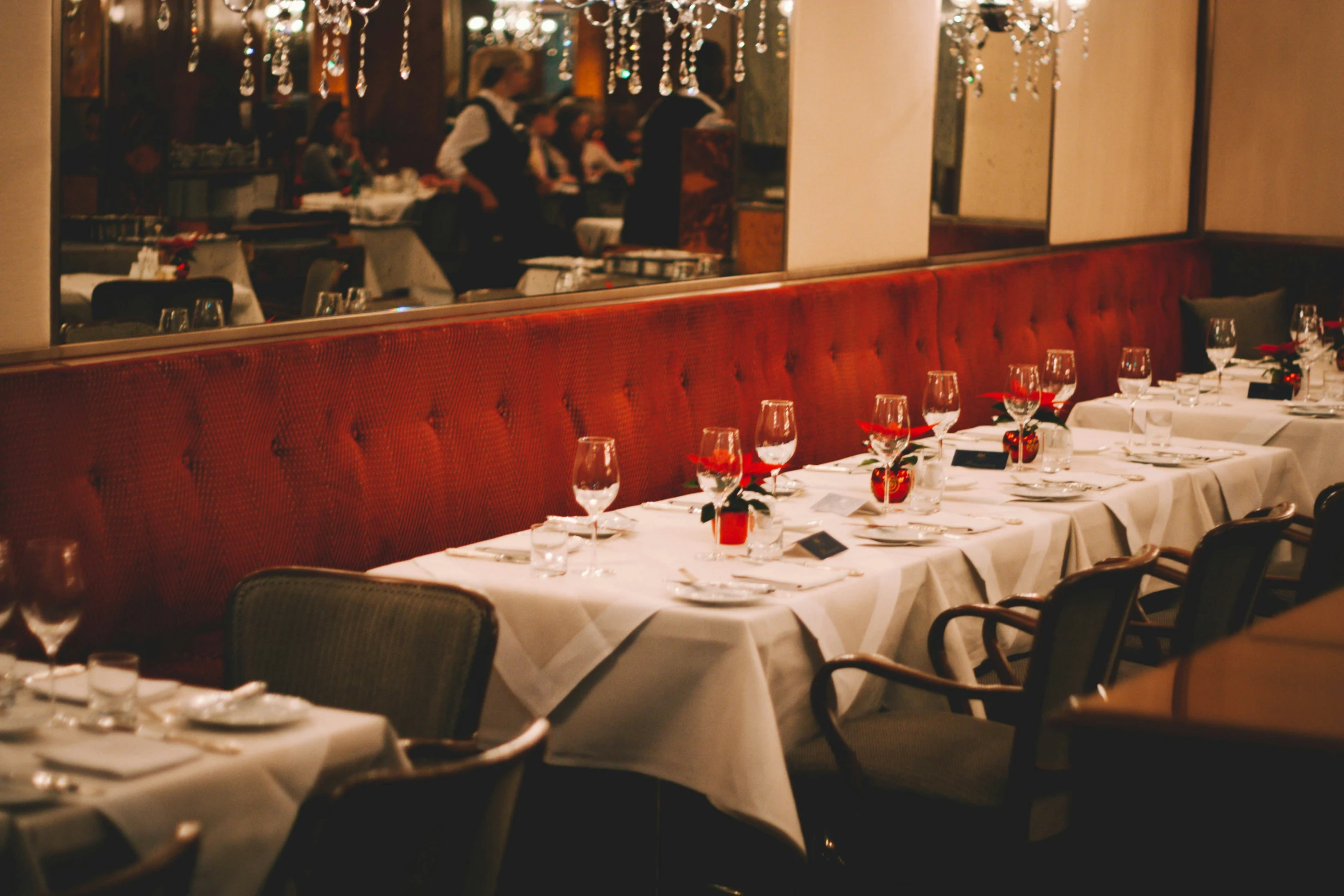 a row of empty tables covered with plates of dinnerware