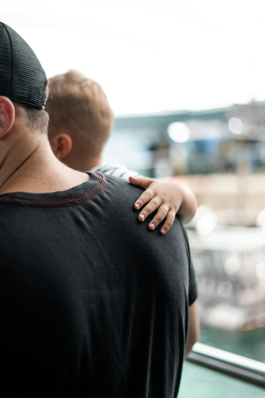 a man with his arm around a child standing on top of a deck