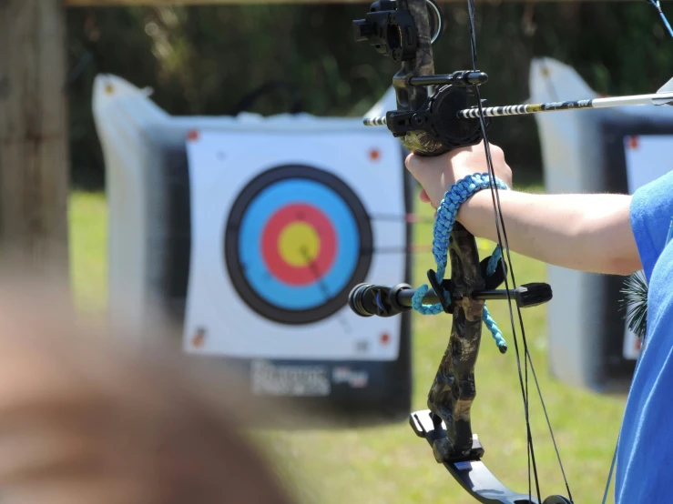 a woman holding a bow in her hand over a archery target