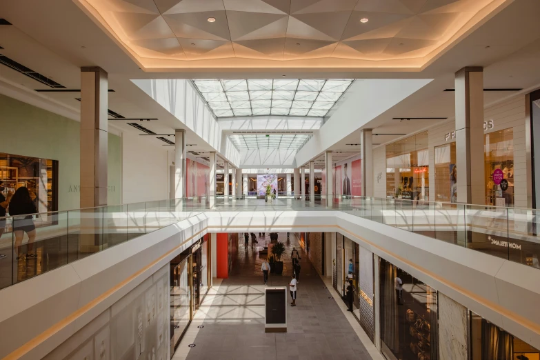 people are walking down an indoor mall in daylight