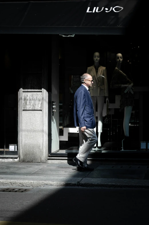 a man walks in the shadow of his store front