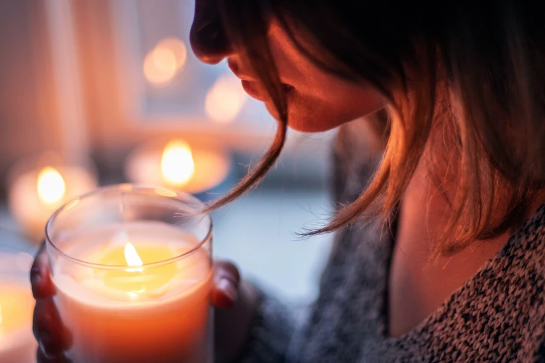 a woman is holding a lit candle inside her hands