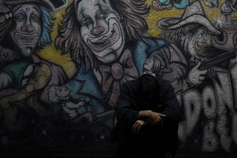 a man sitting in front of graffiti covered wall