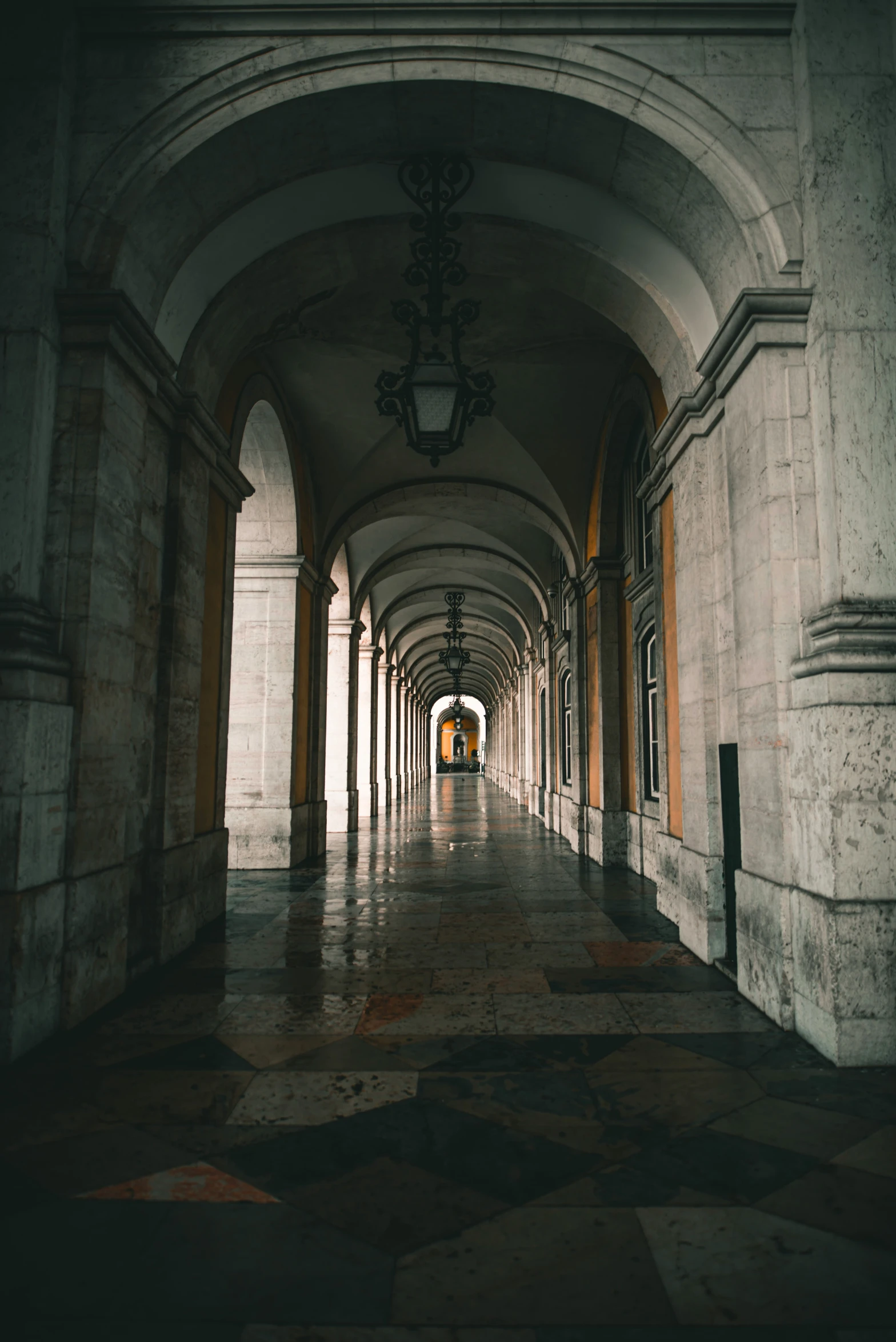 a long hall with an arched roof and black tile on the floor