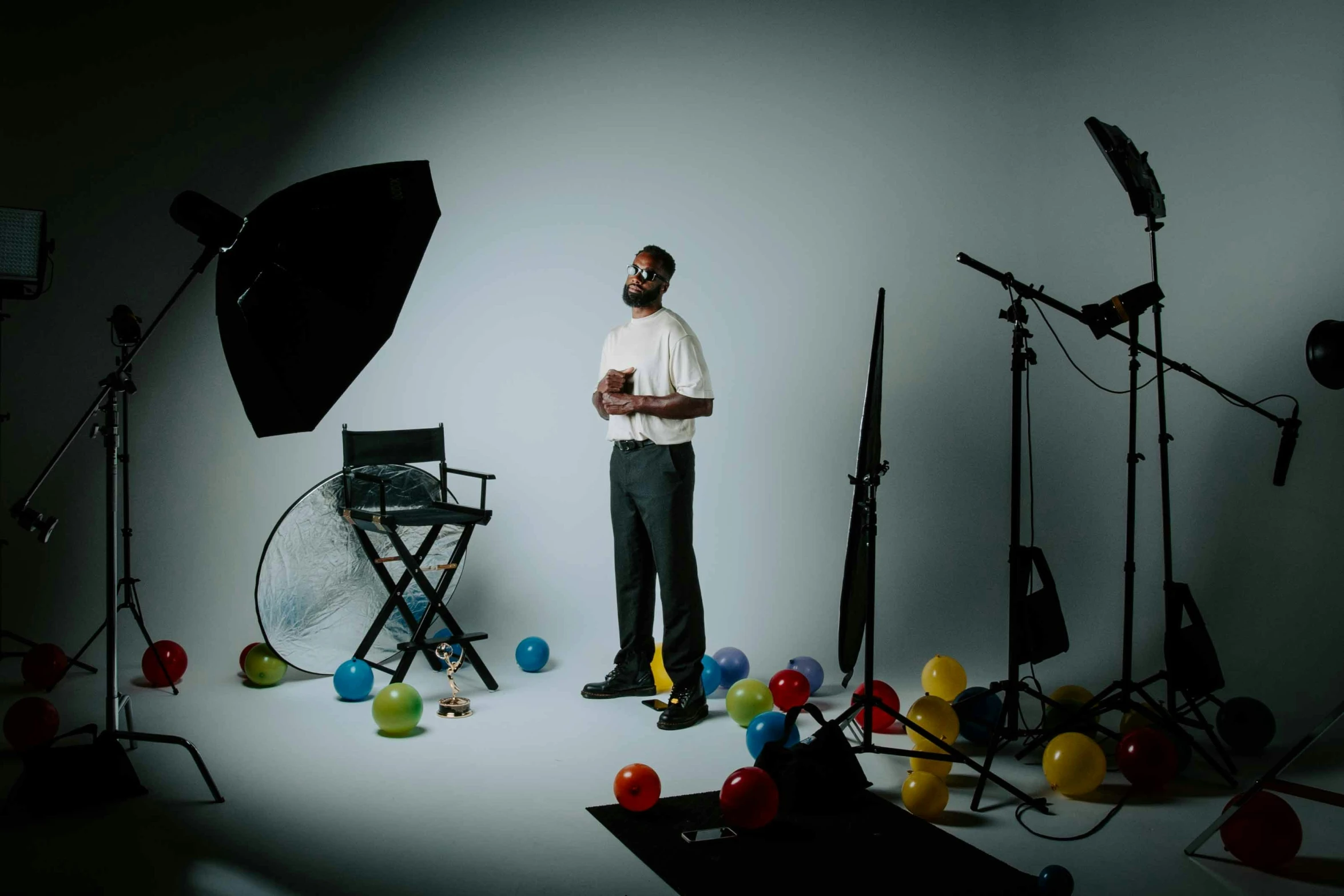 a man stands in front of balloons with camera equipment in the background