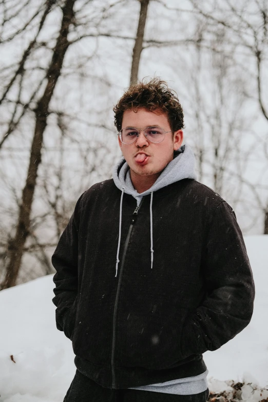 a young man standing in the snow wearing a black hoodie