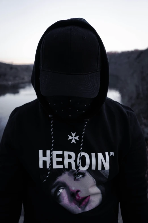 a man wearing a black hoodie and holding a cigarette