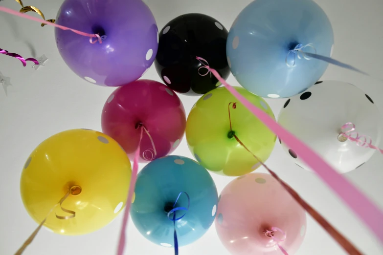 a bunch of small balloons lined up against a white wall