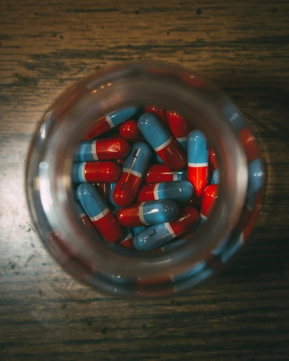 a bunch of red and blue pills are in a jar