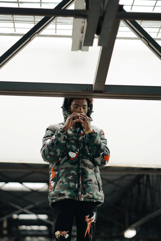 a man wearing an army camouflage jacket takes a pograph in a mirror