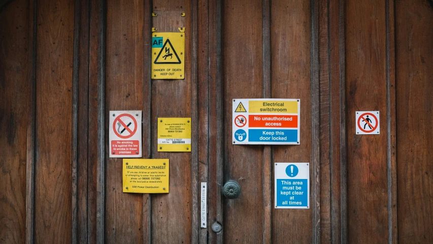some signs on a wood door one is in blue, yellow and red