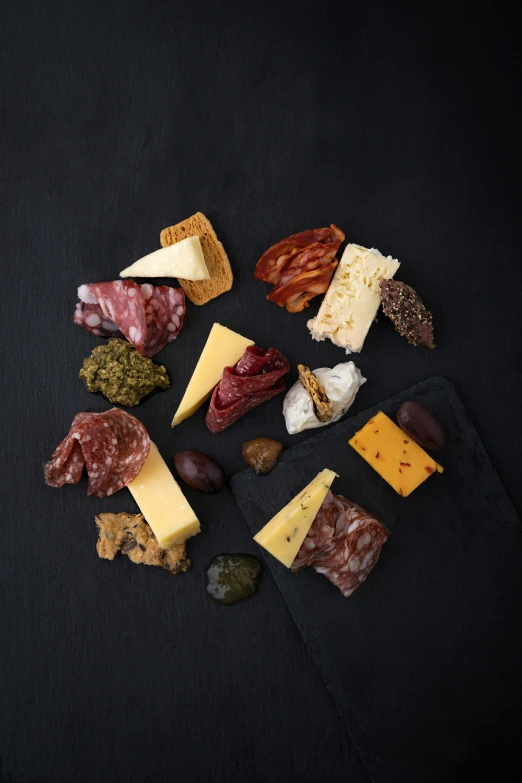 assortment of meats and cheese on a dark background