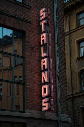 a brick building with windows has a neon sign on top of it