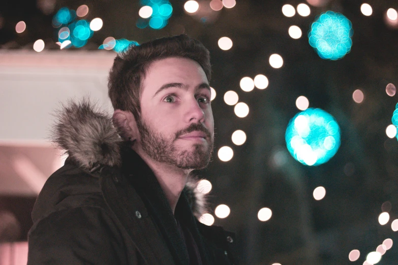 a man standing next to a tree covered in christmas lights