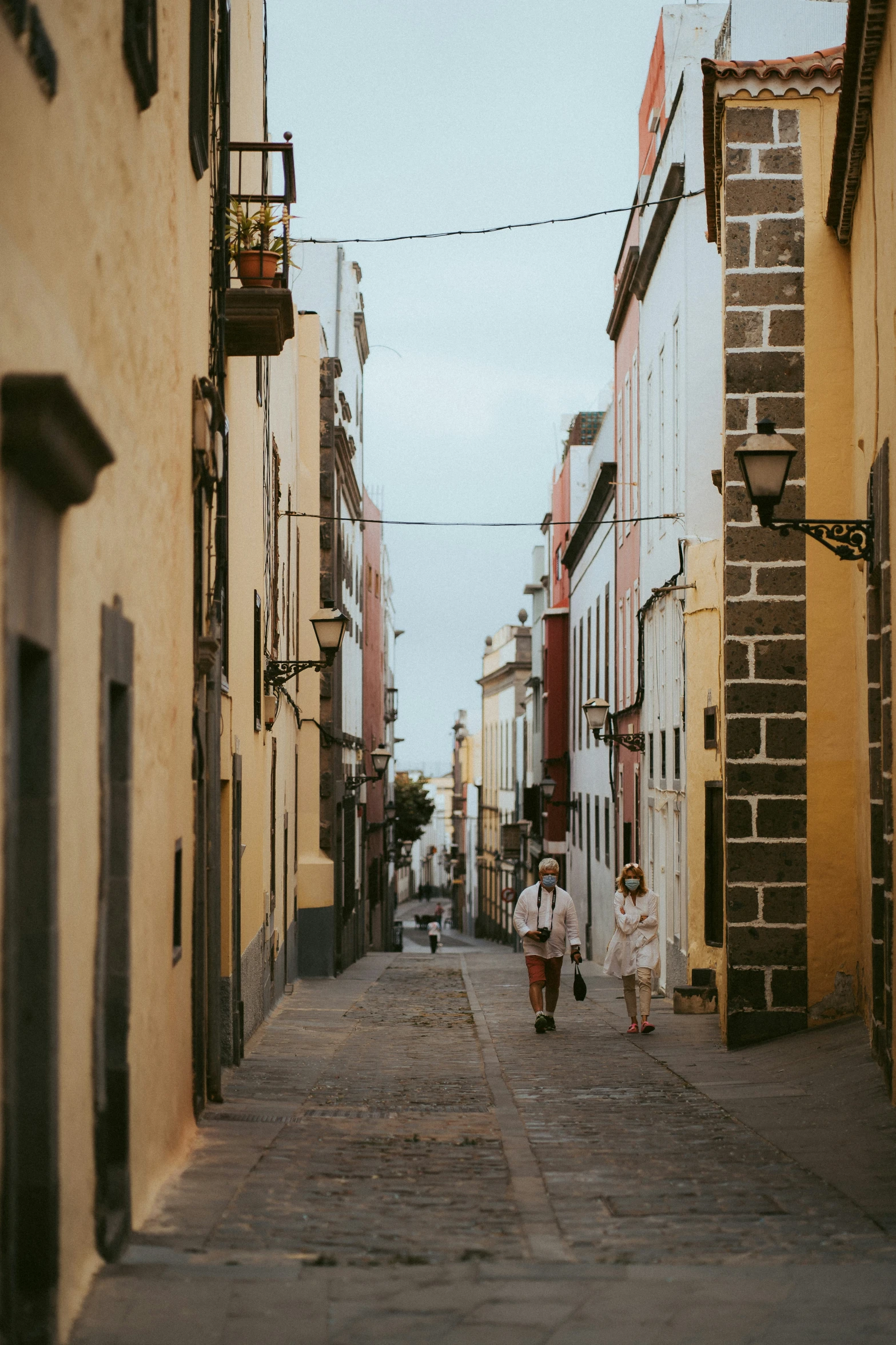 two children walking down an alley way near some buildings