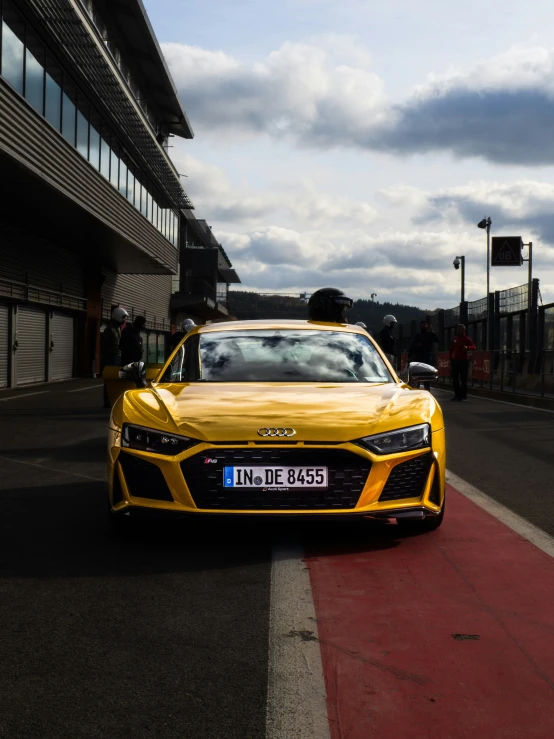 the front of a yellow sports car sitting in front of a large building