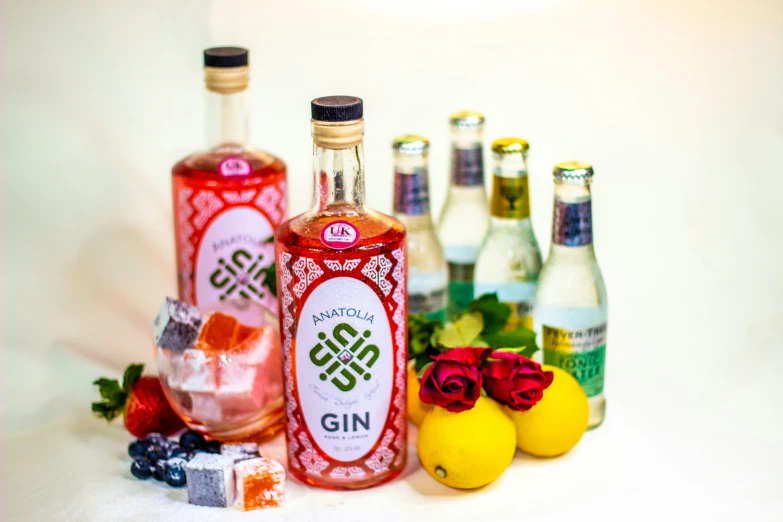 four gin bottles are lined up next to some fruit