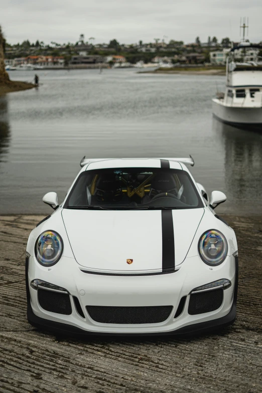 a white sports car parked in front of the water