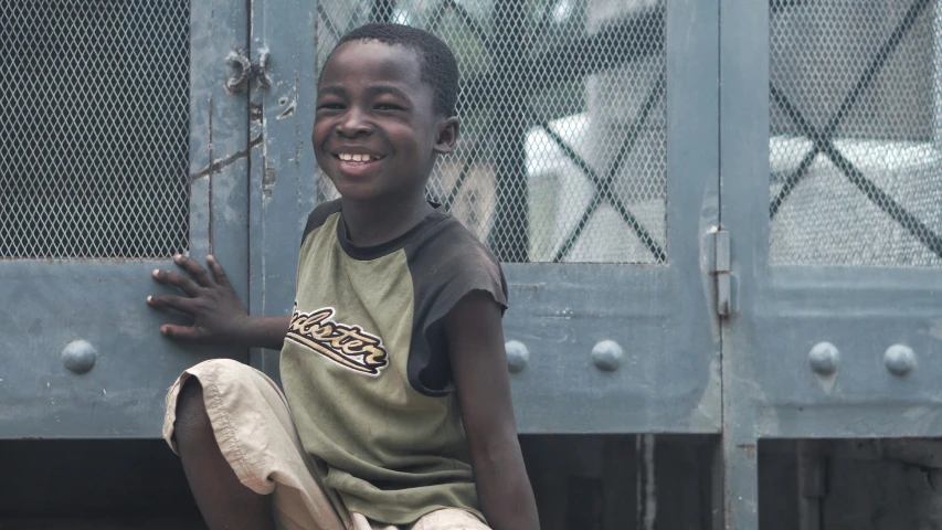 a boy smiles while sitting on the ground