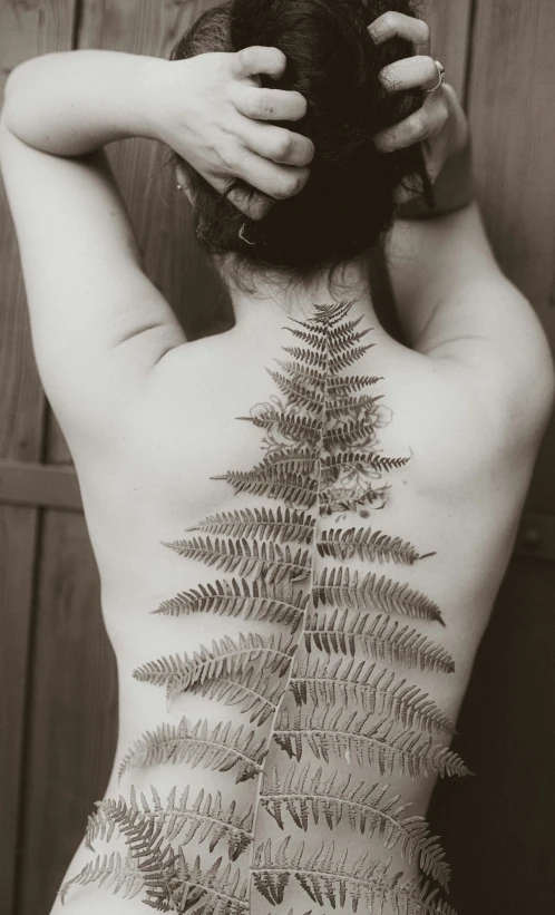 there is a woman showing her back with a plant on it