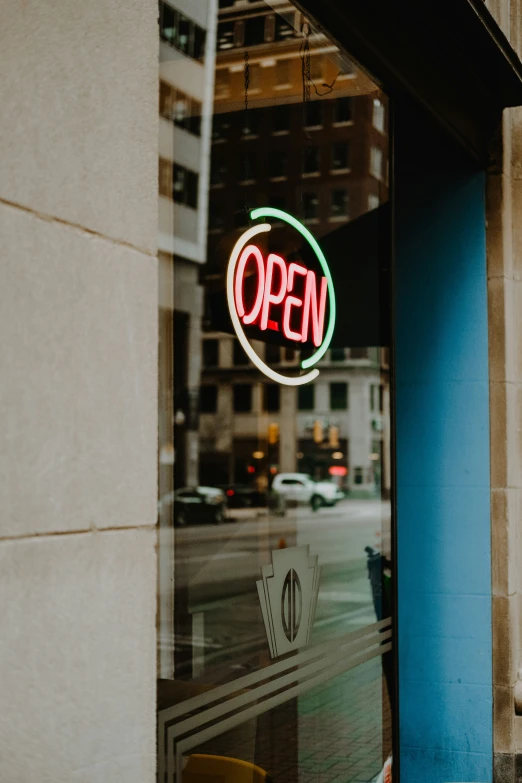 a view out a window into an open neon sign