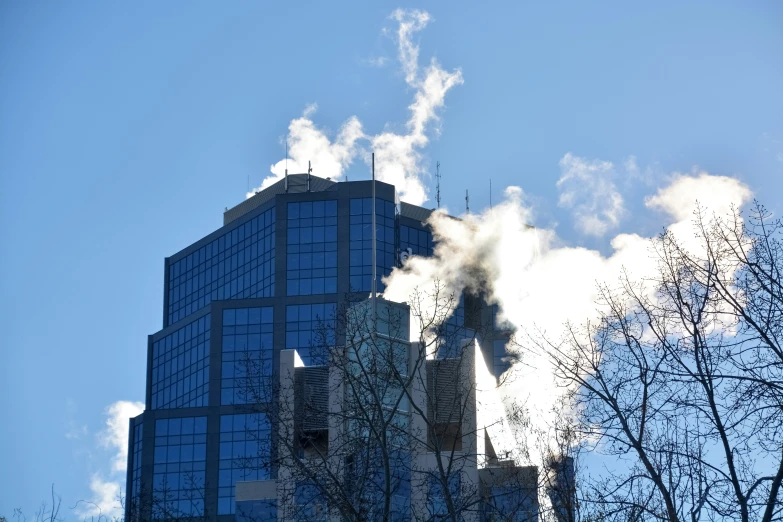 a smokestack on a skyscr rises in the distance as it blows smoke