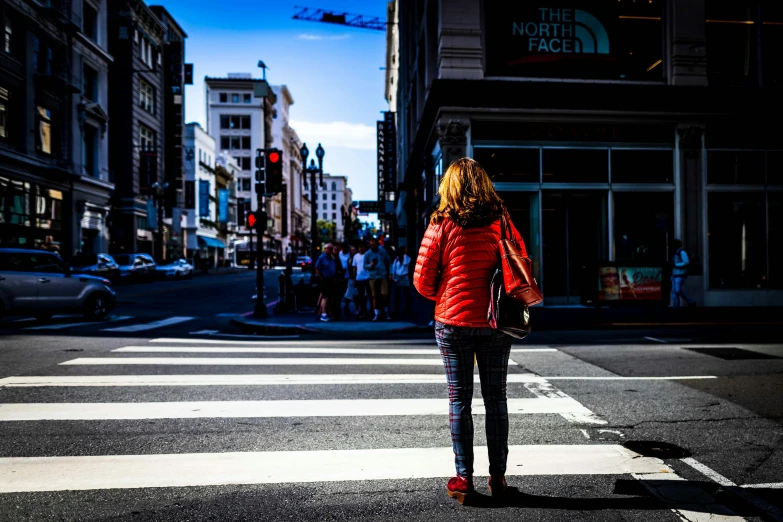 a woman in red coat standing at crosswalk