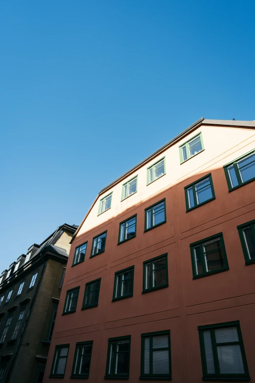 the corner of a building with windows facing toward a blue sky