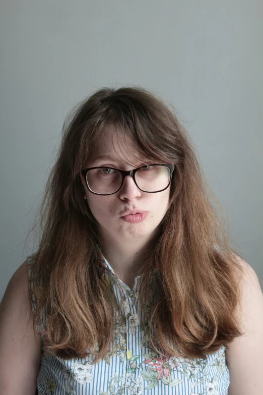 a woman with glasses sitting in front of a wall