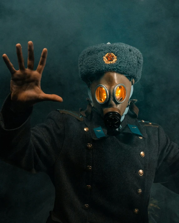 a man dressed in gas mask and blue cap making hand gestures