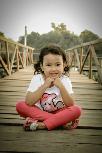 little girl sitting on a bridge posing for a po