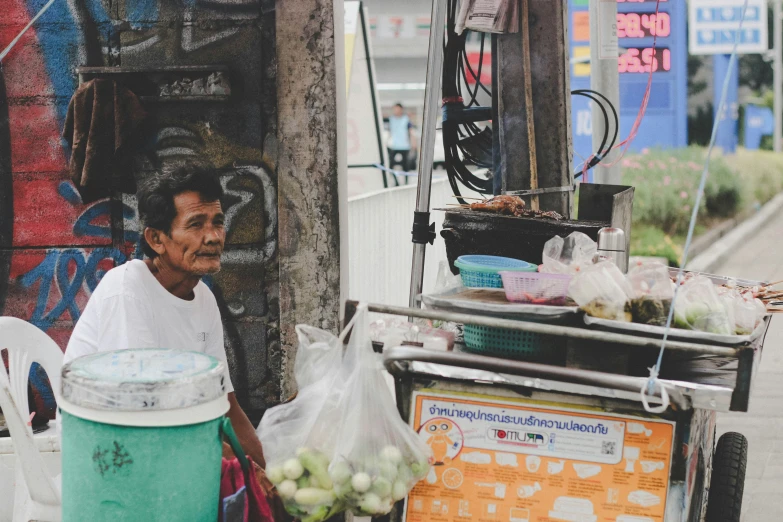 an old man is next to a food stand