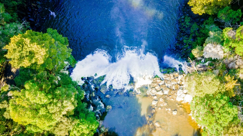 a river running through some green trees and water