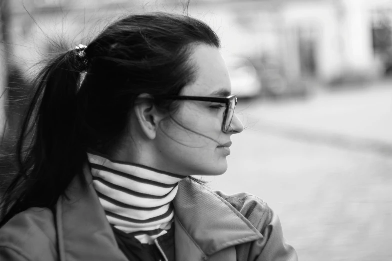 a woman in sunglasses and a jacket wearing a striped neck scarf