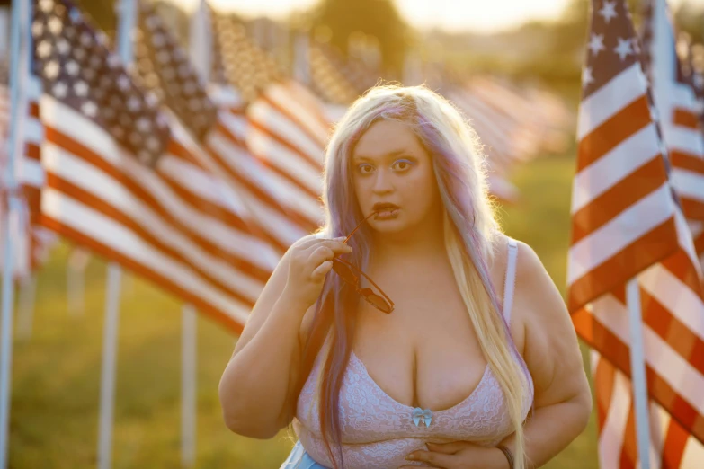 a woman with big  is standing in front of american flags