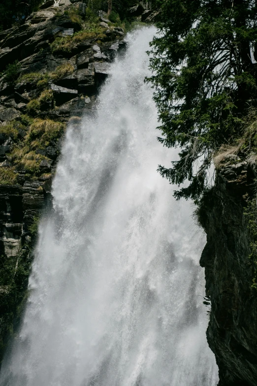 a waterfall with water cascading the sides and a tree growing in it