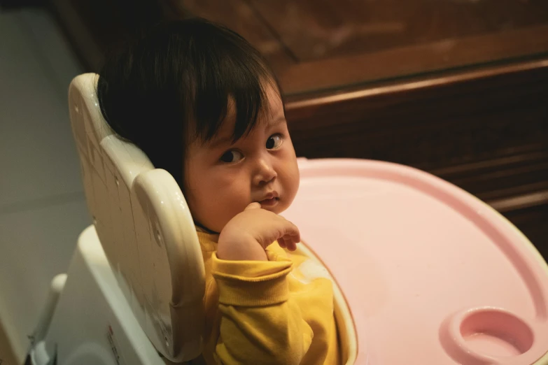 little girl sitting in her high chair and smiling at the camera