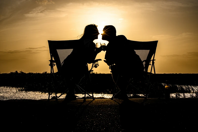 two people sitting in chairs while the sun sets