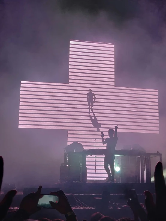 a po of a guy on stage with a giant cross