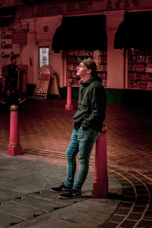 a man in blue jeans stands by a red post